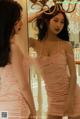 A woman in a pink dress standing in front of a mirror.