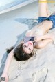 A woman laying on the sand on a beach.