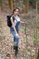 A woman with a backpack standing in the woods.