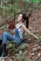 A woman sitting in the woods reading a book.