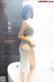 A woman in a white dress standing in a bathroom.