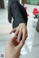 A woman in a business suit is putting a ring on another woman's finger.