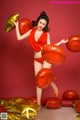 A woman in a red bikini holding a bunch of balloons.