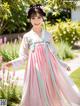 A woman in a pink and blue hanbok is posing for a picture.