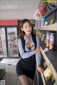 A woman in a skirt and shirt leaning against a shelf in a store.