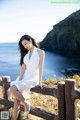 A woman in a white dress sitting on a wooden fence.