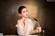 A woman in a white dress is holding a shower head.