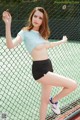 A woman in a blue shirt and black shorts posing on a tennis court.