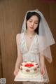 A woman in a wedding dress holding a cake.