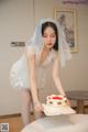 A woman in a wedding dress cutting a cake.