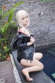 A woman in a black leather jacket and shorts posing by a pool.