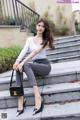 A woman sitting on the steps of a building with a handbag.