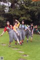 A group of young women standing on top of a lush green field.