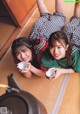 Two young women laying on the floor with cups of tea.