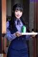 A woman in a blue suit holding a can of soda.