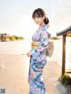 A woman in a blue and pink kimono standing by the water.