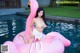 A woman in a white bikini sitting on an inflatable flamingo.