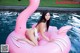 A woman in a white bikini sitting on a pink flamingo float.