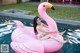 A woman in a white bathing suit sitting on a pink flamingo float.