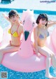 Two young women in bikinis sitting on an inflatable flamingo in a pool.