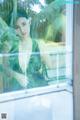 A woman in a green dress looking out of a window.