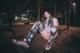 A woman sitting on a bench in a park at night.