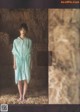 A woman standing in front of a pile of hay.