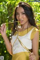 A woman in a yellow and white dress holding a stick.