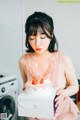 A woman in a pink dress holding a birthday cake.