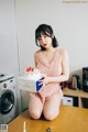 A woman sitting on a kitchen counter holding a box of strawberries.