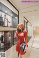 A woman in a red dress standing in front of a display case.