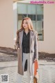 A woman in a gray coat is walking down the street.