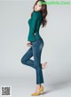 a woman in a green sweater and jeans posing for a picture