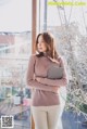 A woman standing in front of a window holding a laptop.