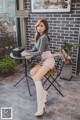 a woman sitting on a chair in front of a brick wall