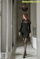 A woman in a black dress is walking down a hallway.