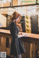 A woman standing at a bar in a black dress.