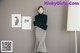 A woman standing in front of a wall with pictures on it.