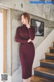 a woman in a burgundy sweater dress standing on a staircase