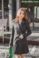 a woman in a black and white striped coat is walking down the street