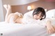 A woman laying on a bed in a white lingerie.