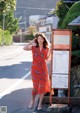 A woman in a red dress standing next to a sign.