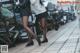 A couple of women walking down a sidewalk next to a row of motorcycles.