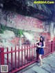 A woman standing in front of a red fence.