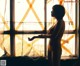 A woman standing in front of a window in a yellow lingerie.