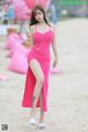 A woman in a pink dress standing on a beach.