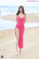 A woman in a pink dress standing on a beach.