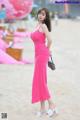 A woman in a pink dress standing on a beach.