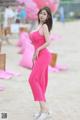 A woman in a pink dress standing on a beach.