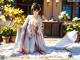 A woman in a white kimono sitting on the ground.